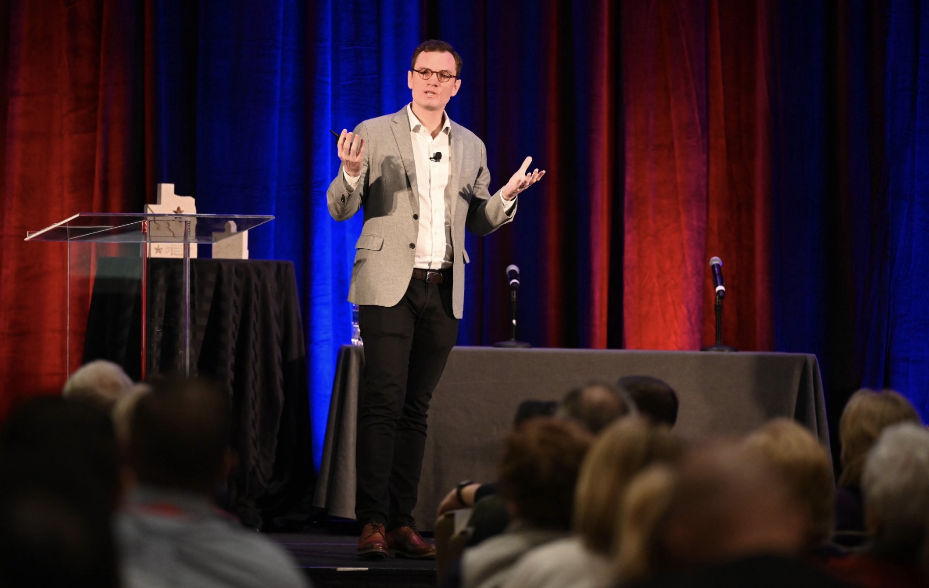 Person giving presentation on stage with blue and red lights